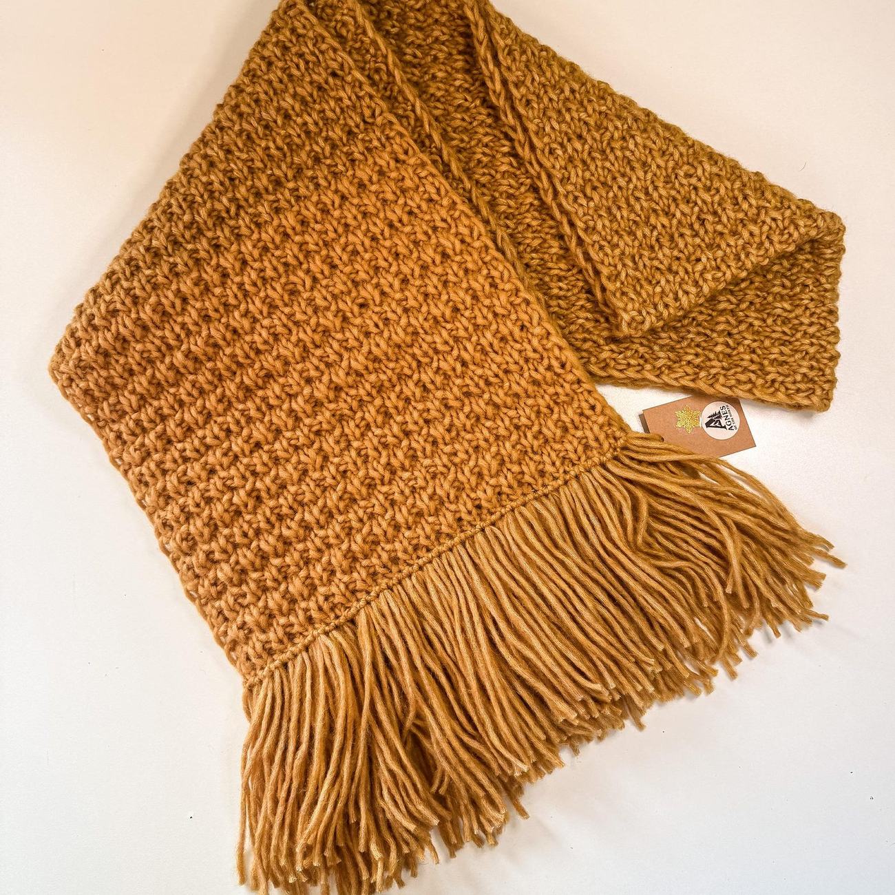 Chunky honey yellow wool scarf with long fringe, folded flat with its kraft tag
