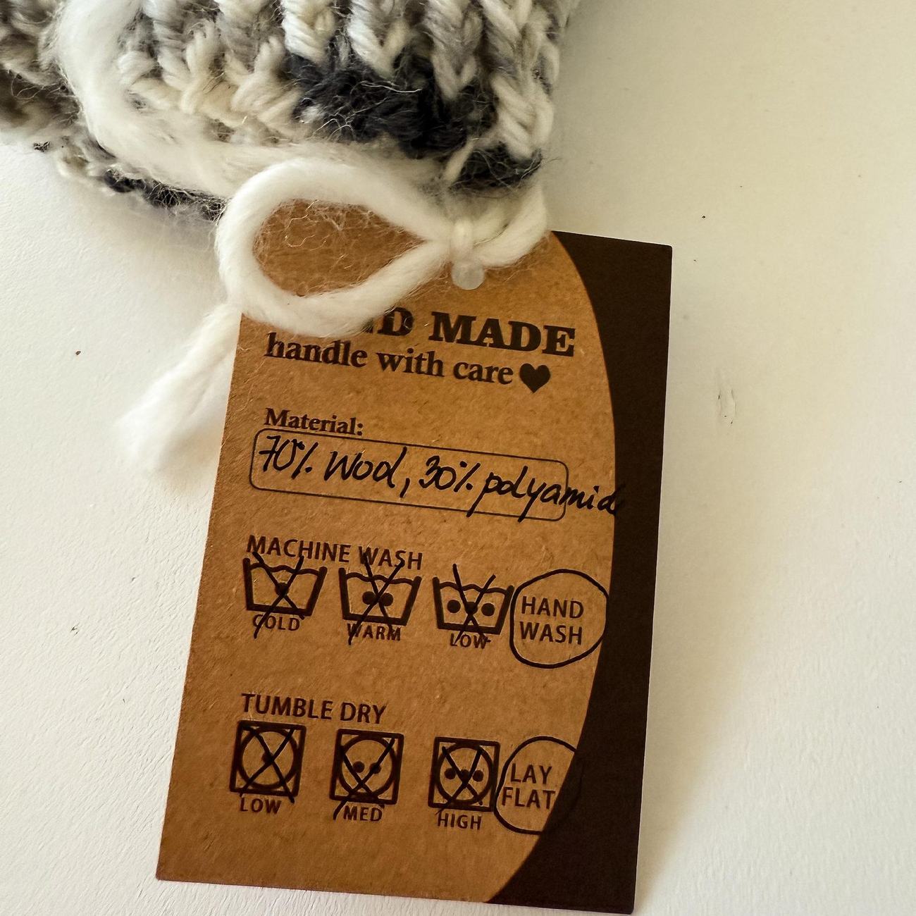 The handwritten kraft hang-tag tied to a finished piece